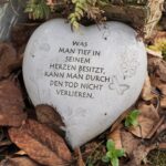 Das Bild zeigt ein Keramikherz mit Spruch: Was man tief in seinem Herzen besitz, kann man durch den Tod nicht verlieren.